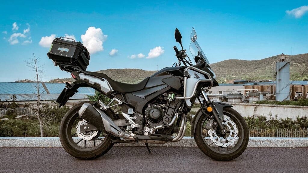 Side view of a modern motorbike parked outdoors with scenic background, perfect for travel themes.